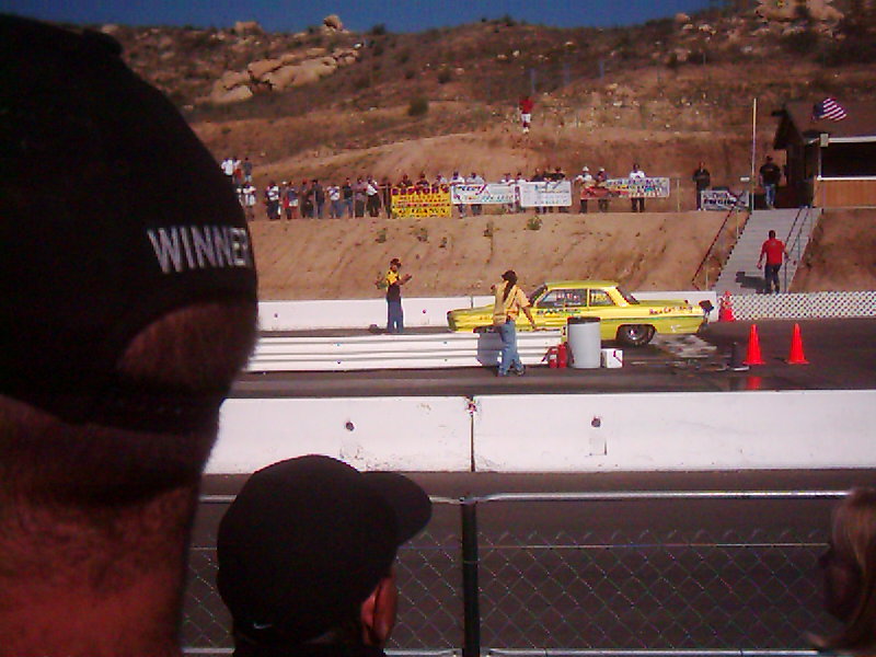 Yellow drag car on track, people watching from stands