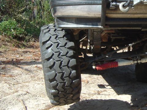 1993 Ford Bronco - The underside of a vehicle with large tires and suspension parts is shown in this outdoor shot.