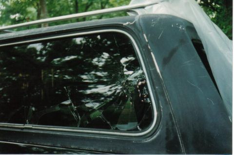 1979 Ford Bronco - The rear side window of a 1979 Ford Bronco is cracked, with a roof rack visible above.