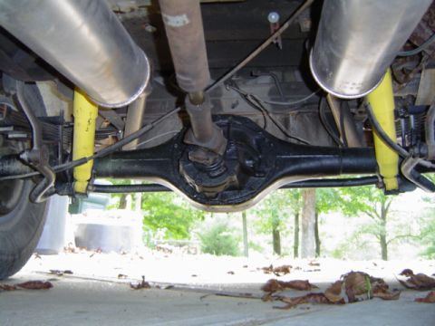 1979 Ford Bronco - Underside view shows the rear axle, driveshaft, and dual exhaust system of a vehicle.