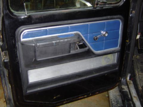 1979 Ford Bronco - The interior door panel features blue vinyl inserts and a ribbed metal lower section.