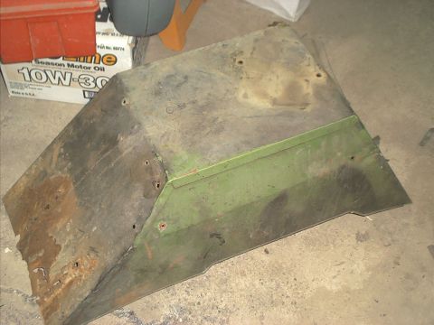 1966 Ford Bronco - A heavily rusted metal panel, possibly a fender or body section, shows signs of green paint and numerous mounting holes.