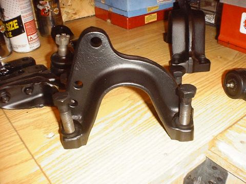 1988 Ford Bronco - Close-up of a vehicle's front axle part, likely a control arm or bracket, on a wooden surface.