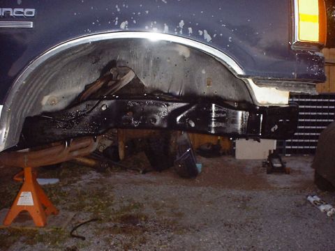 1988 Ford Bronco - The front axle assembly of a dark blue vehicle is shown supported by jack stands.