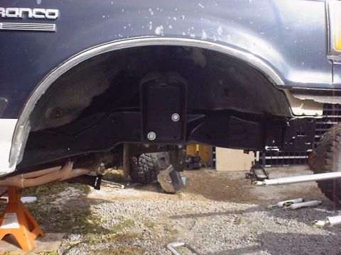 1988 Ford Bronco - Close-up view of the undercarriage and suspension of a vehicle, with the 'Bronco' emblem visible on the body.