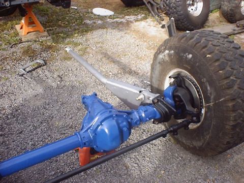 1988 Ford Bronco - A blue front axle assembly is shown next to a large off-road tire, possibly undergoing maintenance or modification.