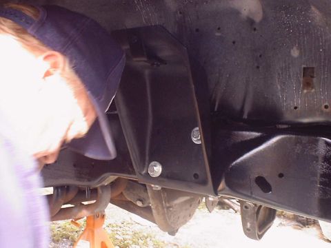 1988 Ford Bronco - A bracket is being installed on the underside of a vehicle frame.