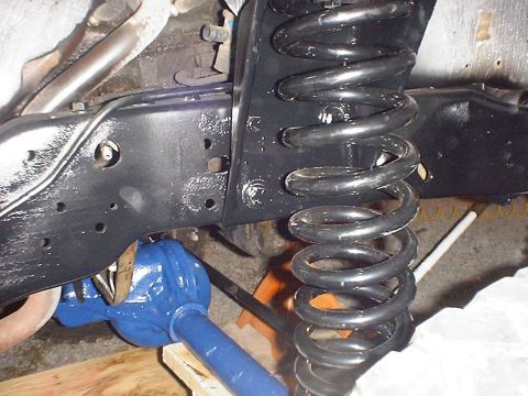 1988 Ford Bronco - The front axle and suspension components of a vehicle are shown, with a focus on the coil spring.