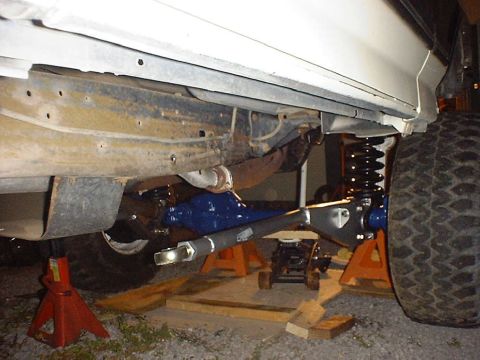1988 Ford Bronco - Close-up view of a vehicle's front axle assembly, a bright blue differential and suspension components, supported by jack stands.