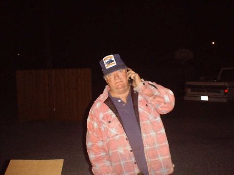 1988 Ford Bronco - A man stands outside at night, talking on his phone with a truck visible in the background.