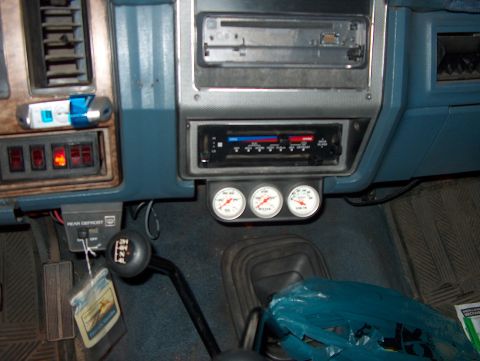 1986 Ford Bronco - Interior view of a vehicle's dashboard, showing gauges, a shifter, and a car stereo system.