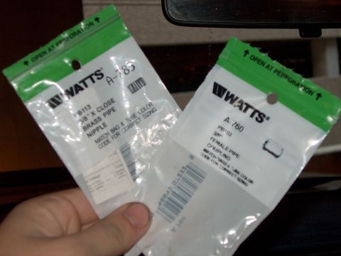 1986 Ford Bronco - Two bags of Watts plumbing fittings, one for a 3/8" brass pipe nipple and the other for a 3/8" female pipe coupling, are held in hand.