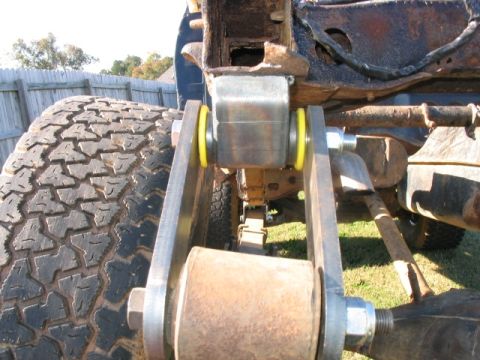 1986 Ford F-150 - Custom suspension parts are installed on a truck, focusing on the linkage and a large off-road tire.