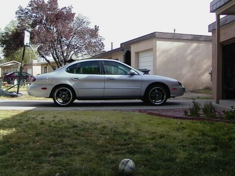 1999 Ford Taurus - A silver sedan is parked in a residential driveway with a house and garage in the background.
