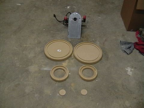 1999 Ford Taurus - A router and various sized wooden rings are laid out on a concrete floor, possibly for a car audio installation.