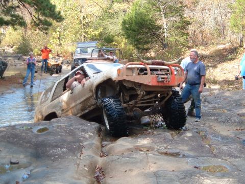 1986 Ford Bronco - This modified SUV is attempting to cross a rocky stream, with another vehicle visible in the background.