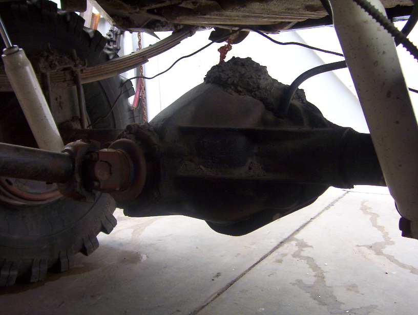 Underside view of a vehicle's rear axle, leaf springs, and shock absorber