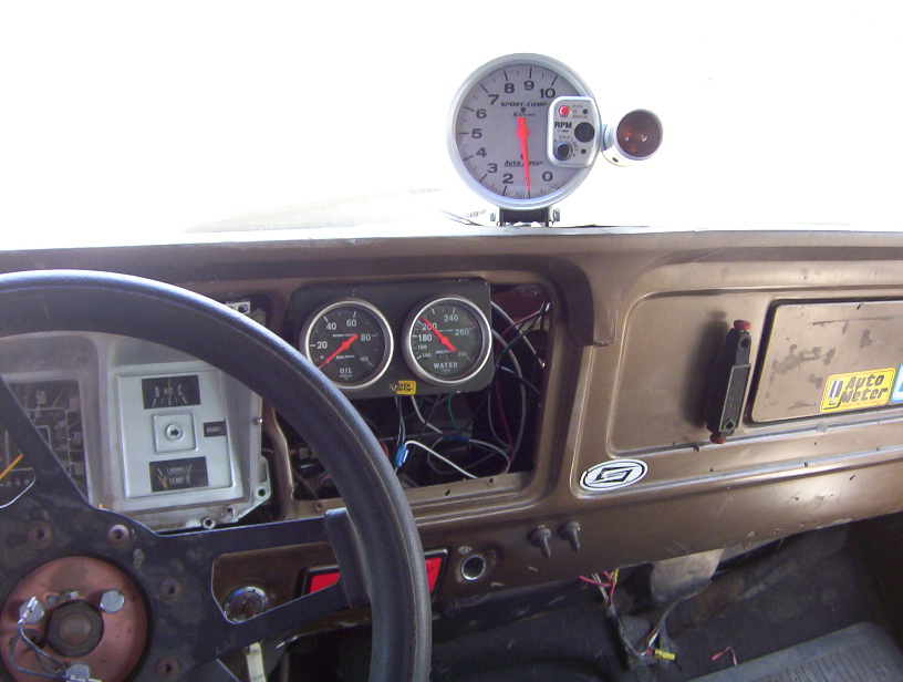 Truck dash with Auto Meter tach mounted on top, water and oil gauges, GT steering wheel