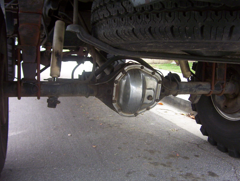 Underside view of solid rear axle, differential cover, leaf springs and shock on a truck
