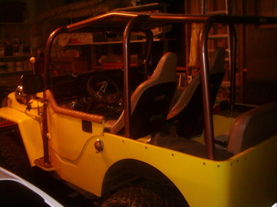 Yellow jeep with roll cage and bucket seats, viewed from the front three-quarter angle
