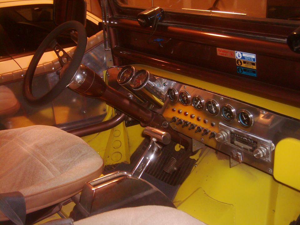 Interior view of a vehicle with a custom dashboard, multiple gauges, switches, and a floor shifter
