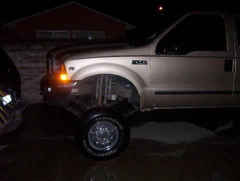 2000 Ford F-450 - This gold Ford F-450 pickup truck is shown in a 3/4 front view, highlighting its lifted suspension.