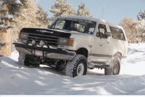 1990 Ford Bronco - This 1990 Ford Bronco is navigating a snowy terrain with its tires kicking up snow.