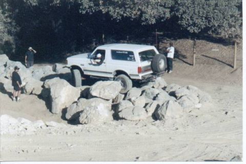 1990 Ford Bronco - A white 1990 Ford Bronco navigates a challenging rocky obstacle course.