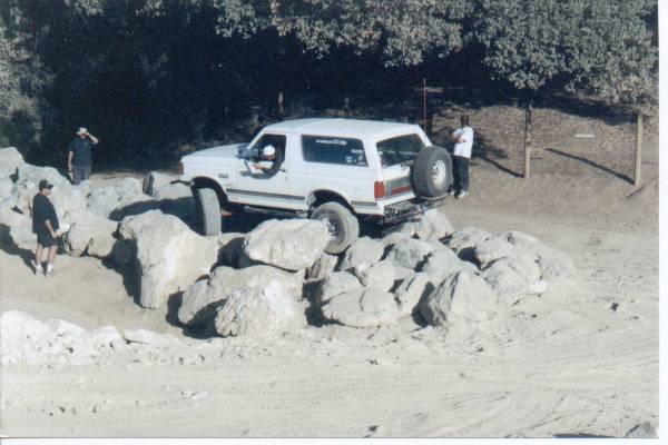 White 1990 Ford Bronco on rocky terrain, rear-mounted spare tire visible