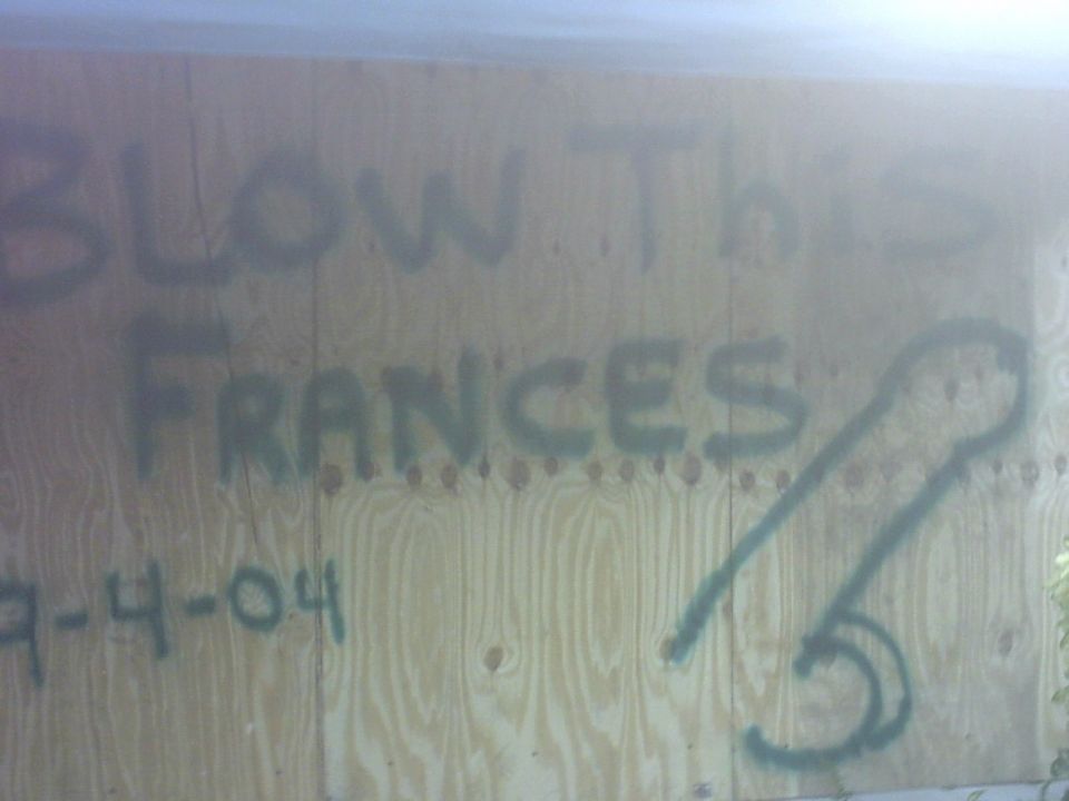 Graffiti on plywood reads 'BLOW THIS FRANCES' with a drawing and '9-4-04'