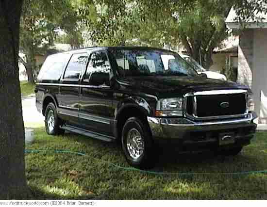Black Ford Excursion SUV parked on grass under a tree, chrome grille and wheels