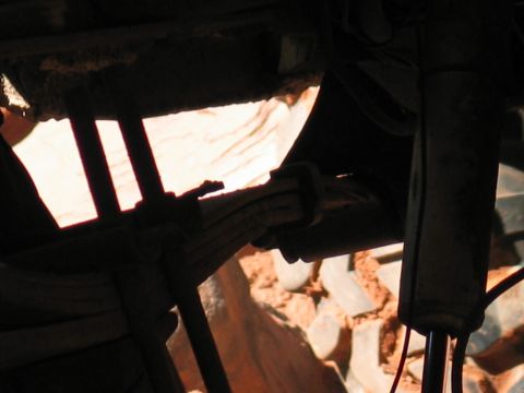 1987 Ford Bronco - Underside view of a vehicle's suspension components, including a leaf spring and shock absorber.