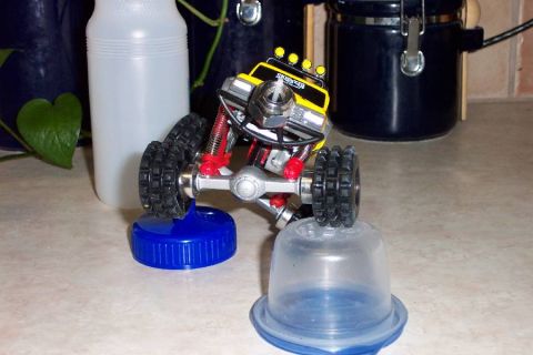 1992 Ford Bronco - A toy monster truck is elevated on bottle caps, with household items in the background.