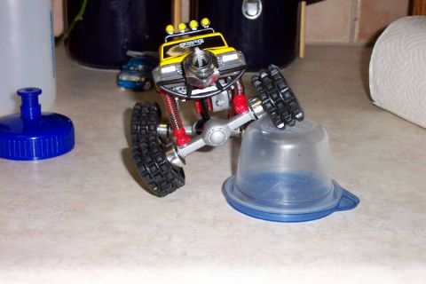 1992 Ford Bronco - A toy monster truck is positioned on a countertop, appearing to climb over a clear plastic container.
