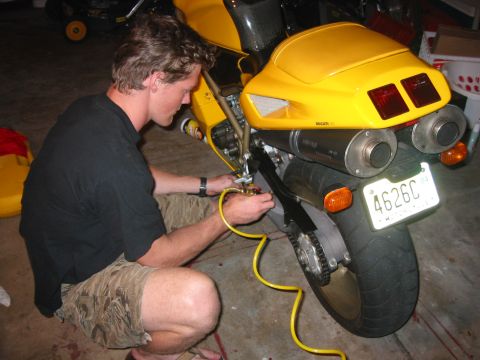 1989 Ford Bronco - Man performs maintenance on a yellow Ducati motorcycle in a garage.