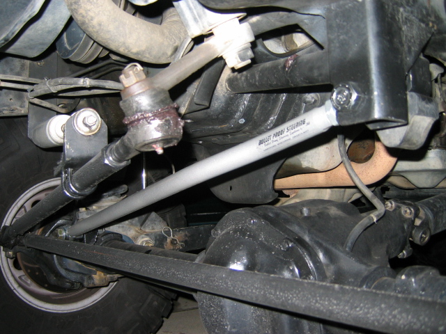 Underside front steering with silver Bullet Proof Steering tie rod and ball joints on a Ford Bronco.