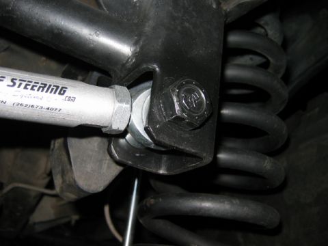 1985 Ford Bronco - A close-up view of a steering component, showing text and a phone number, connected to the vehicle's suspension system.