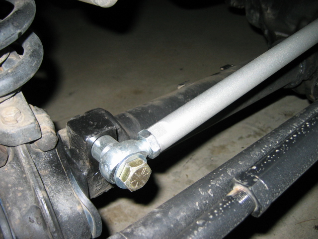Silver suspension rod bolted to undercarriage with gold hex nut, coil spring at left