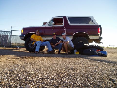 1990 Ford Bronco - A group of friends relax next to a Ford Bronco on a clear day.