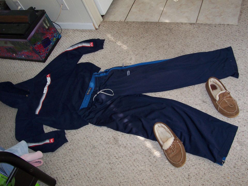Navy blue sweatsuit and two brown moccasin slippers laid out on a carpeted floor