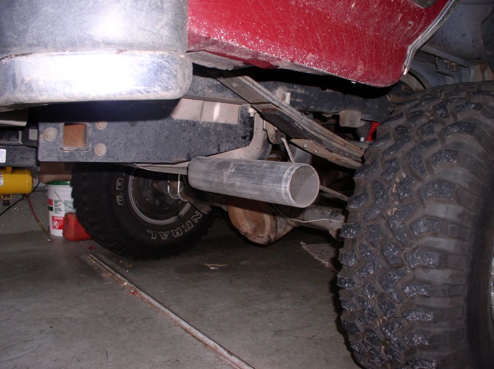 Underside of a vehicle showing exhaust pipe and large tire