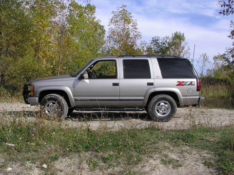 2000 Chevrolet Tahoe - Side view of a silver 2000 Chevrolet Tahoe parked on a dirt road during the fall.