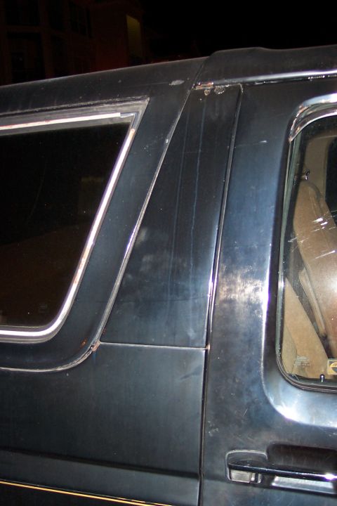1986 Ford Bronco - Close-up of a dark blue SUV's side panel, showing details of the window trim and door handle.
