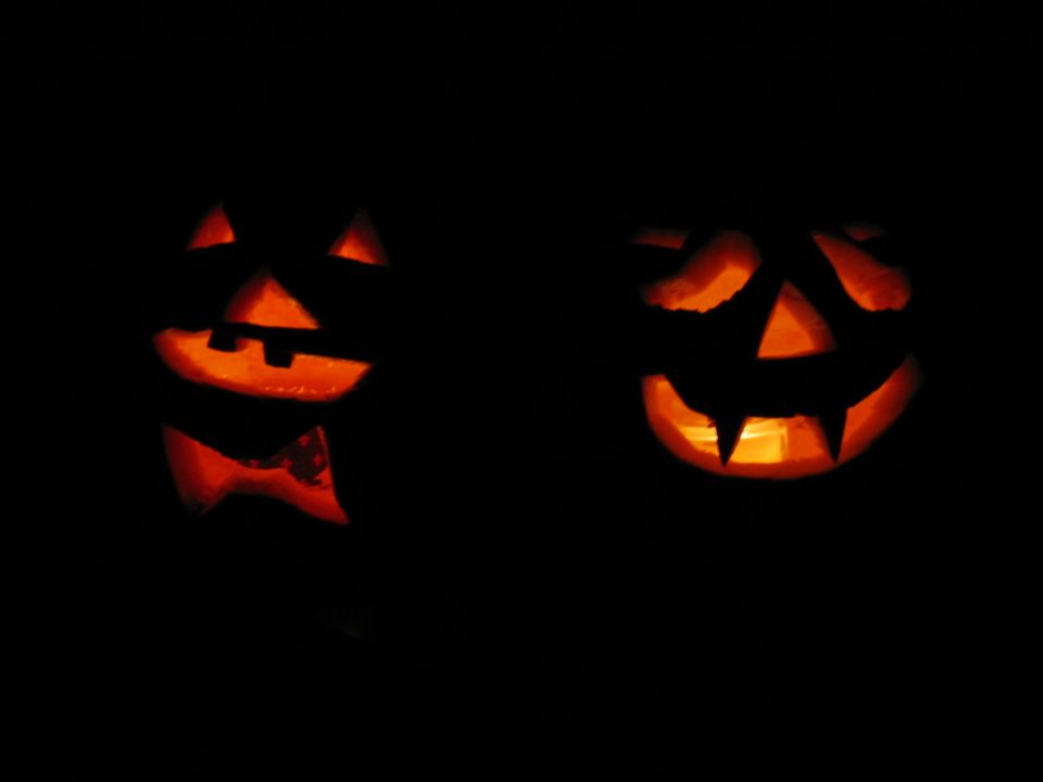 Two carved pumpkins with glowing faces against a black background