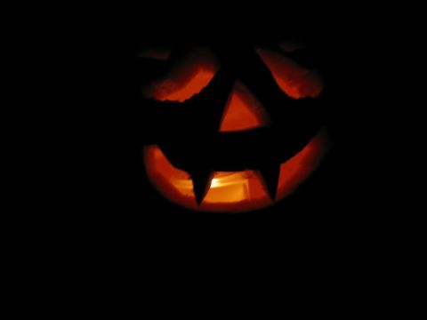 1985 Ford LTD Crown Victoria - A carved pumpkin glows with an internal light against a black background.