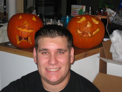 1985 Ford LTD Crown Victoria - A man poses for a photo with two jack-o'-lanterns on a counter.