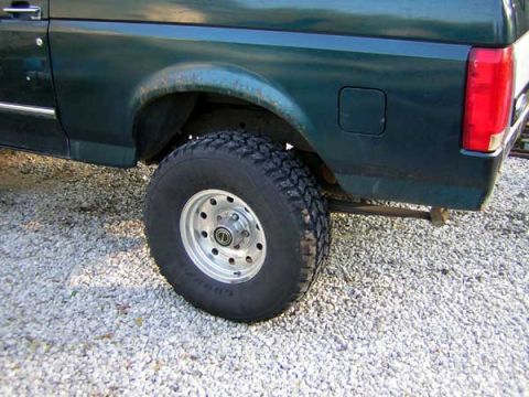 1995 Ford Bronco - The rear side of a green Ford Bronco is visible, with a focus on the tire and fender.