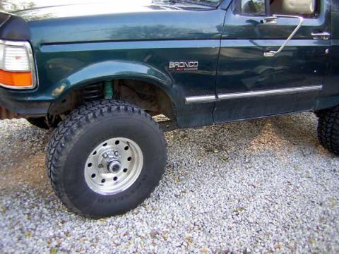 1995 Ford Bronco - Side view of a green 1995 Ford Bronco, highlighting its large tire and fender detail.