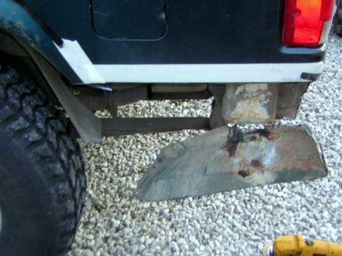 1995 Ford Bronco - Close-up view of the rear bumper and tire of a vehicle, showing signs of rust and damage.
