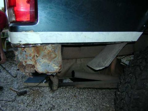 1995 Ford Bronco - The rear bumper mounts and frame of a vehicle show significant rust damage.